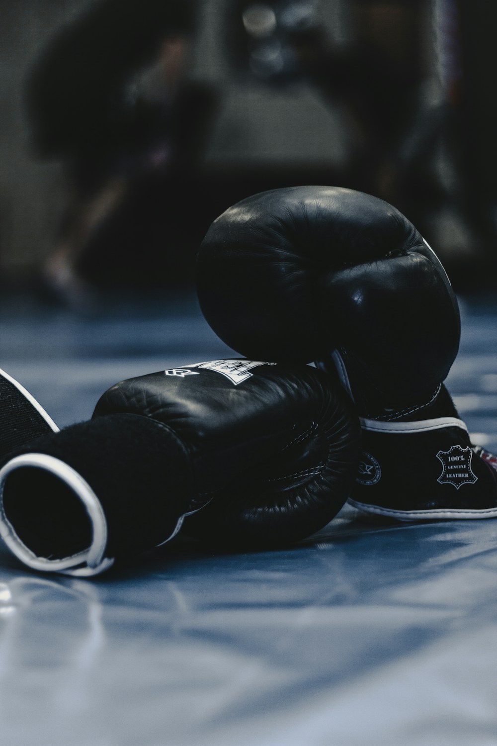 Black boxing gloves resting on a blue training mat