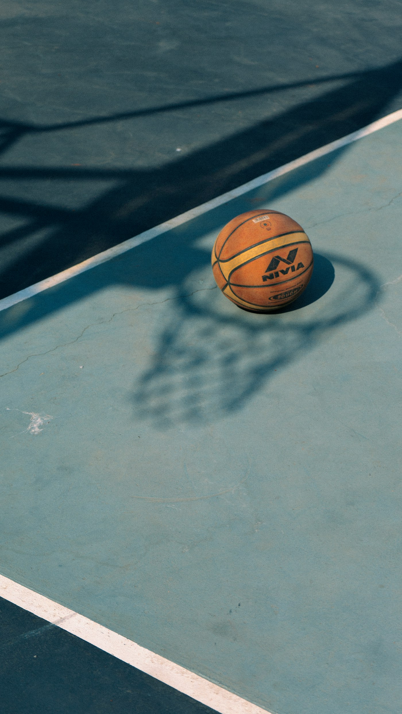 Basketball on a sunlit blue outdoor court